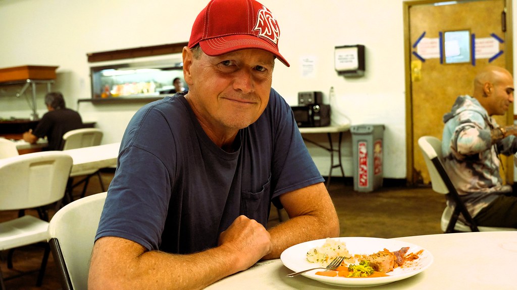 Man in a red cap seated with a plate of Thanksgiving food